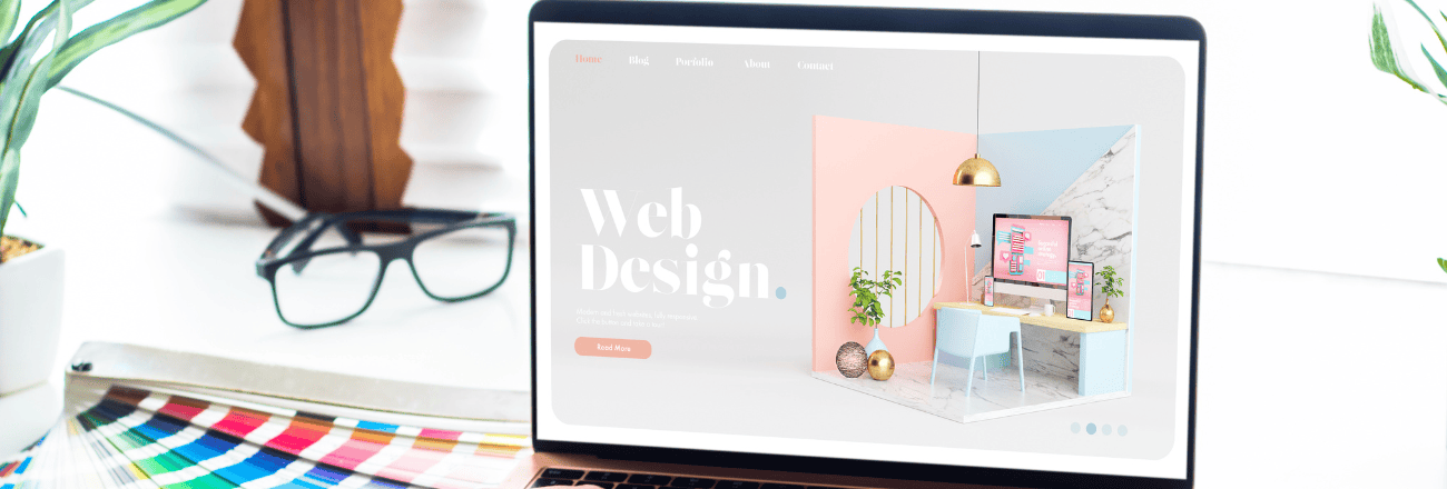 Laptop on a white desk showing a web design portfolio on screen, with color swatches and glasses nearby.