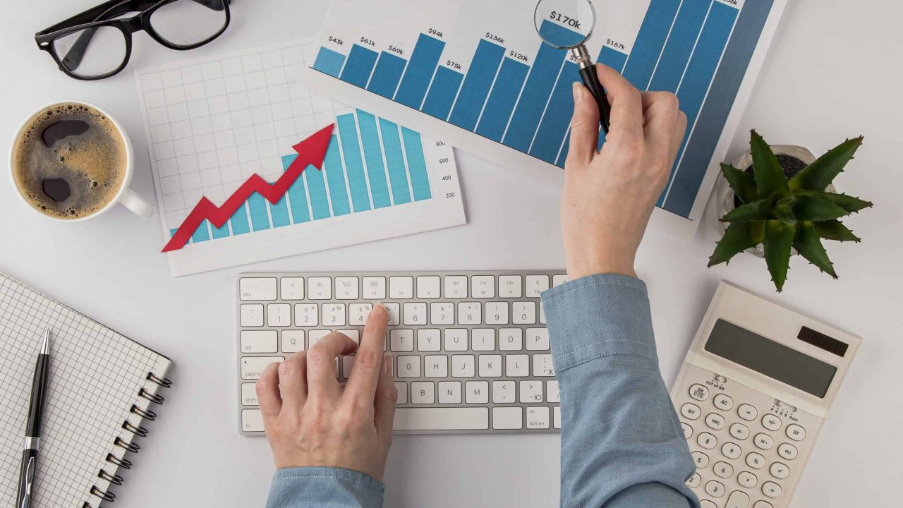 top-view-office-desk-with-growth-chart-hands-with-keyboard top-view-office-desk-with-growth-chart-hands-with-keyboard